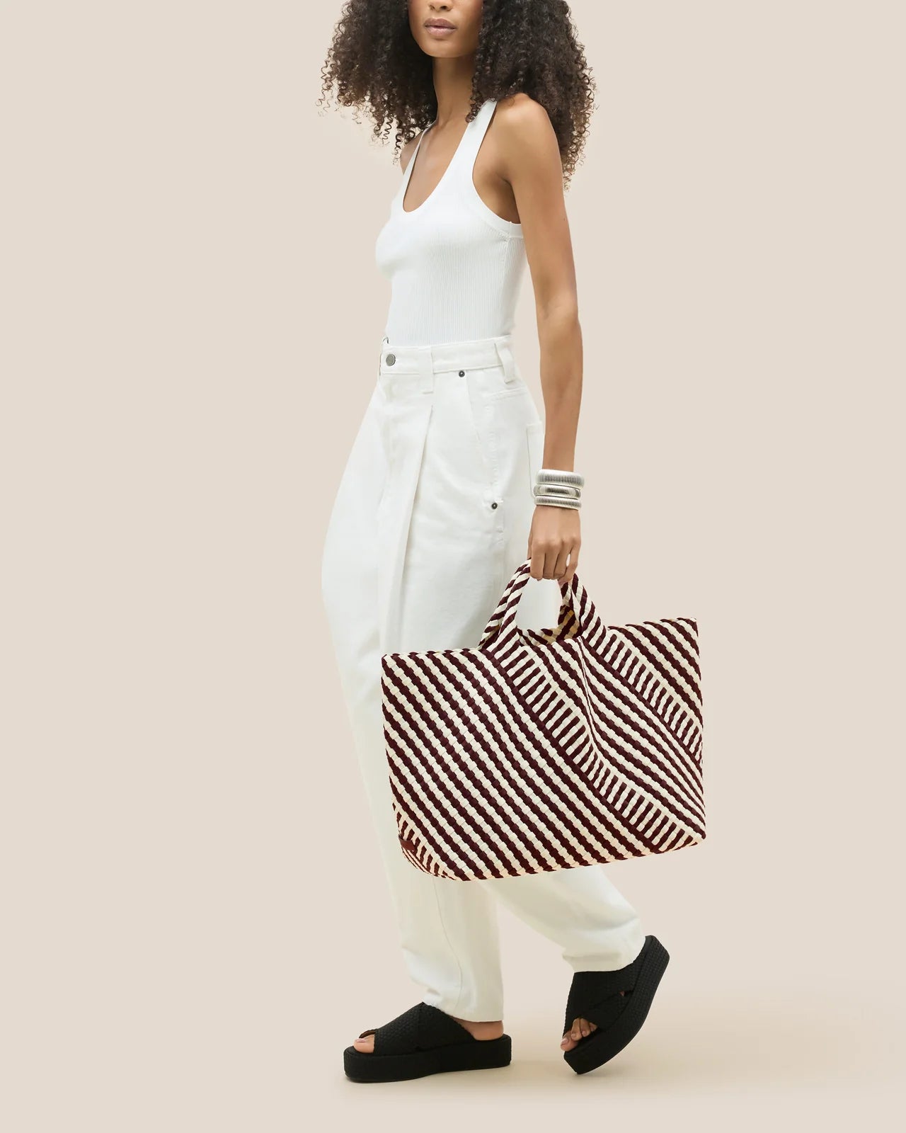 Woman holding a striped bag against a beige background