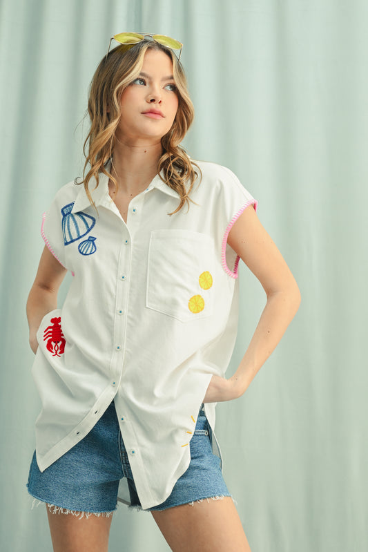 Woman wearing a white shirt with colorful patches against a light curtain background