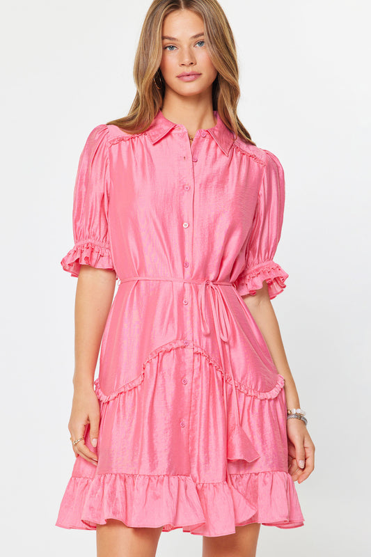 Woman wearing a pink dress with ruffled sleeves and bottom hem on a white background