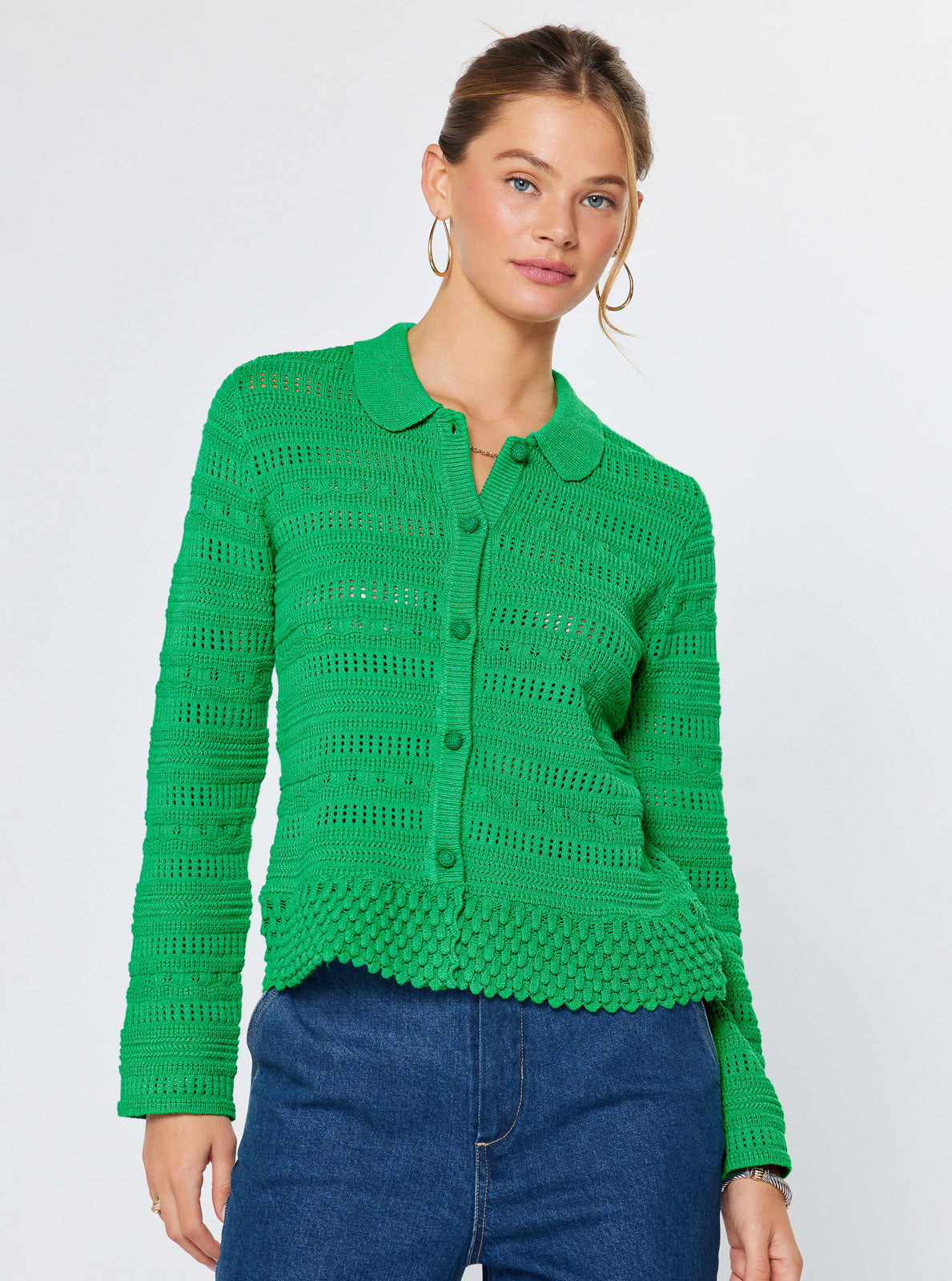 Woman wearing a green knitted cardigan against a white background