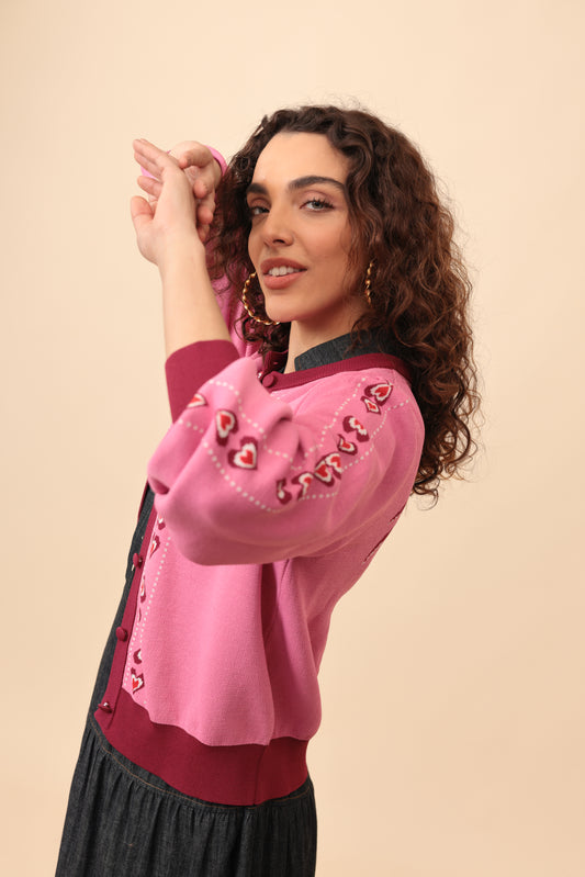 Woman wearing a pink blouse with decorative buttons on a beige background