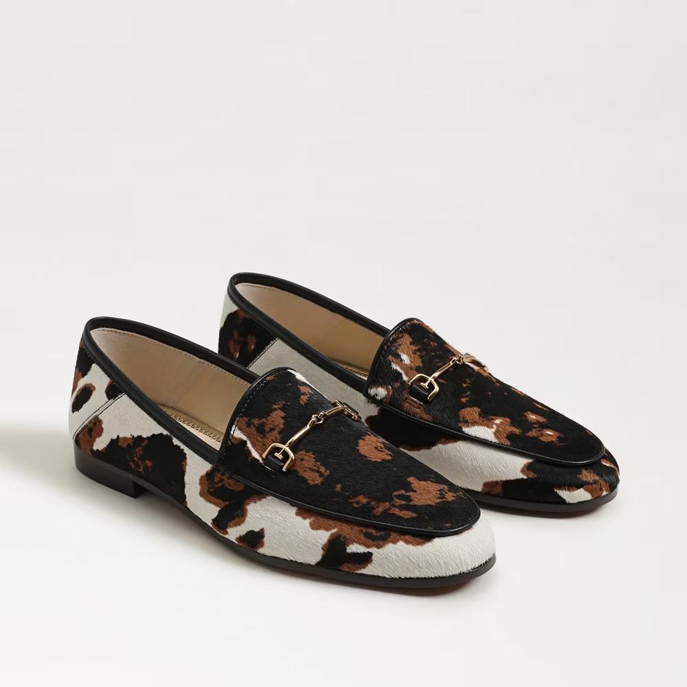 Pair of loafers with cow print pattern on a light gray background