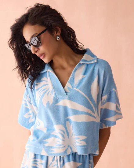 Woman wearing a blue and white floral patterned Omika outfit on a peach background